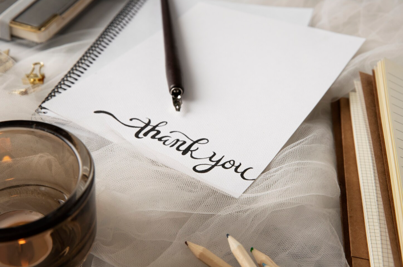Gratitude note with thank you written on paper beside warm drink, noticing the good in everyday.