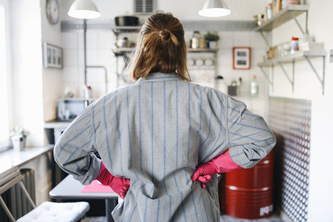 Woman in kitchen planning a weekly home routine before starting household chores.