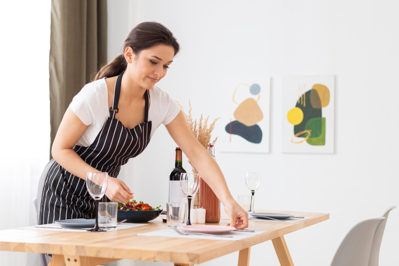 Woman mindfully setting a dining table to create a sacred space at home before guests arrive.