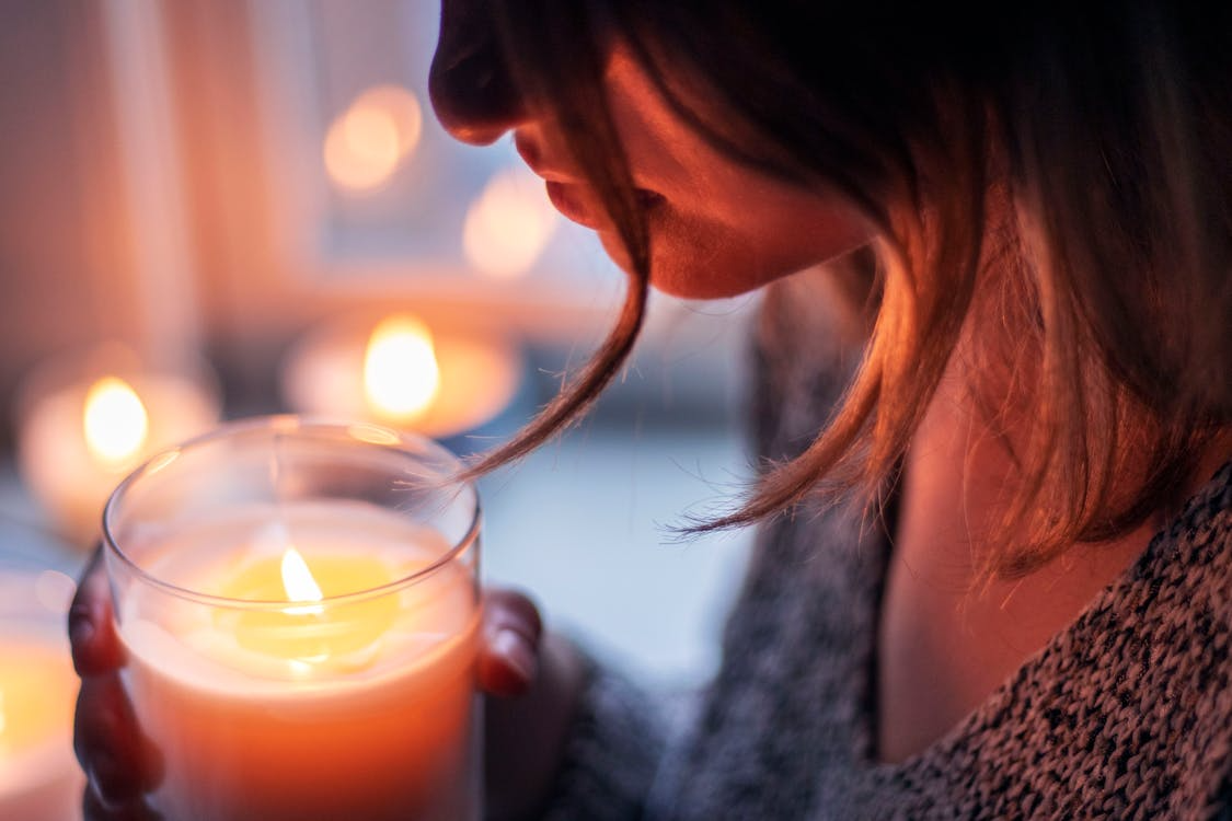 Woman holding a glowing candle during a calming candlelight evening routine.