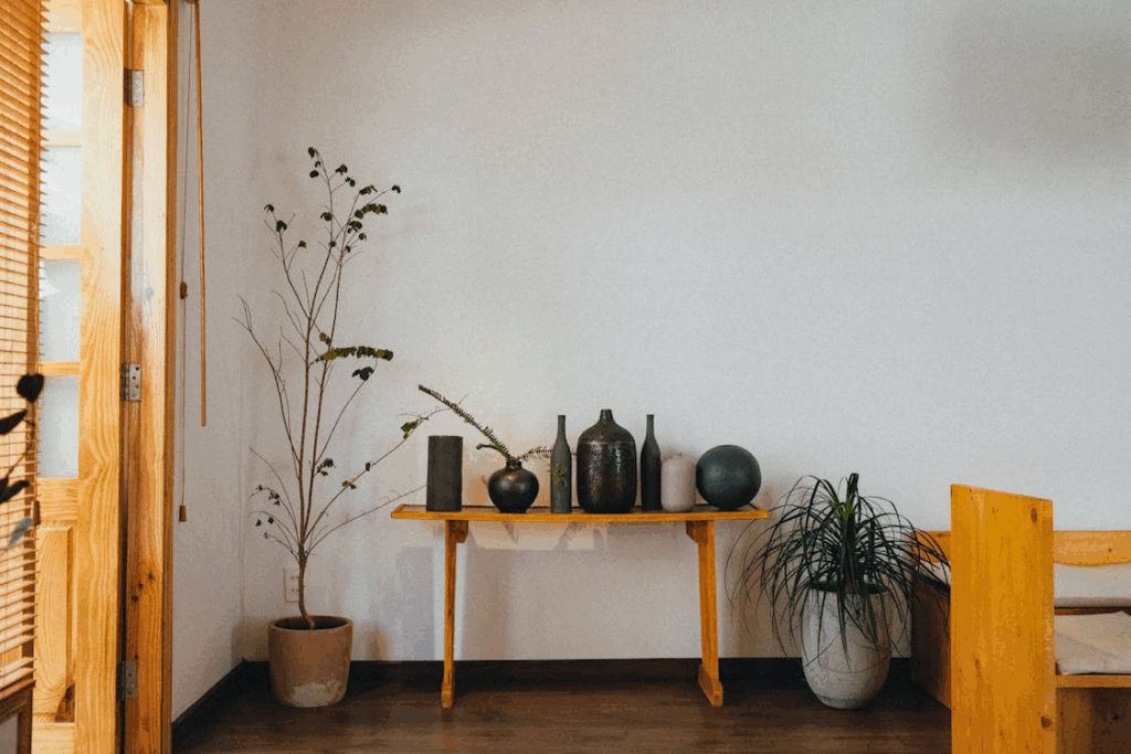 Minimal slow-decorated entryway with wooden console, simple vases, and potted plants.