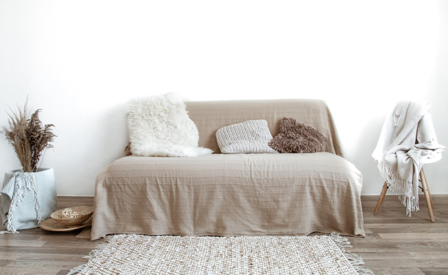 Soft minimalist living room with neutral beige sofa, textured pillows, knit throw and simple decor.