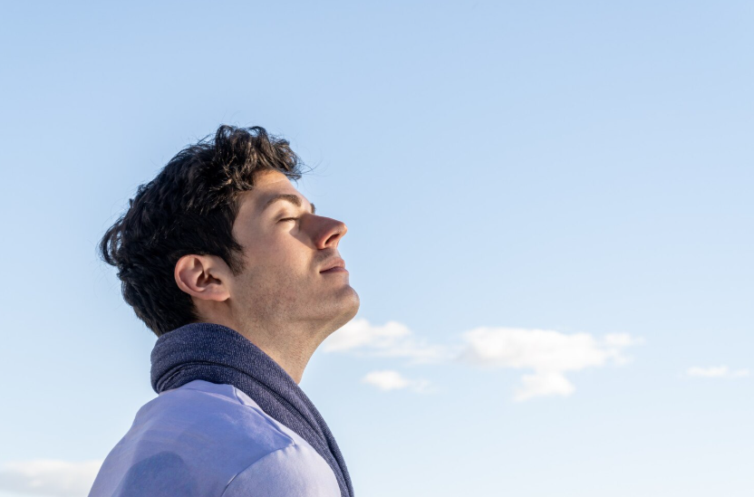 Man calmly breathing outdoors, enjoying the mental health benefits of slowing down