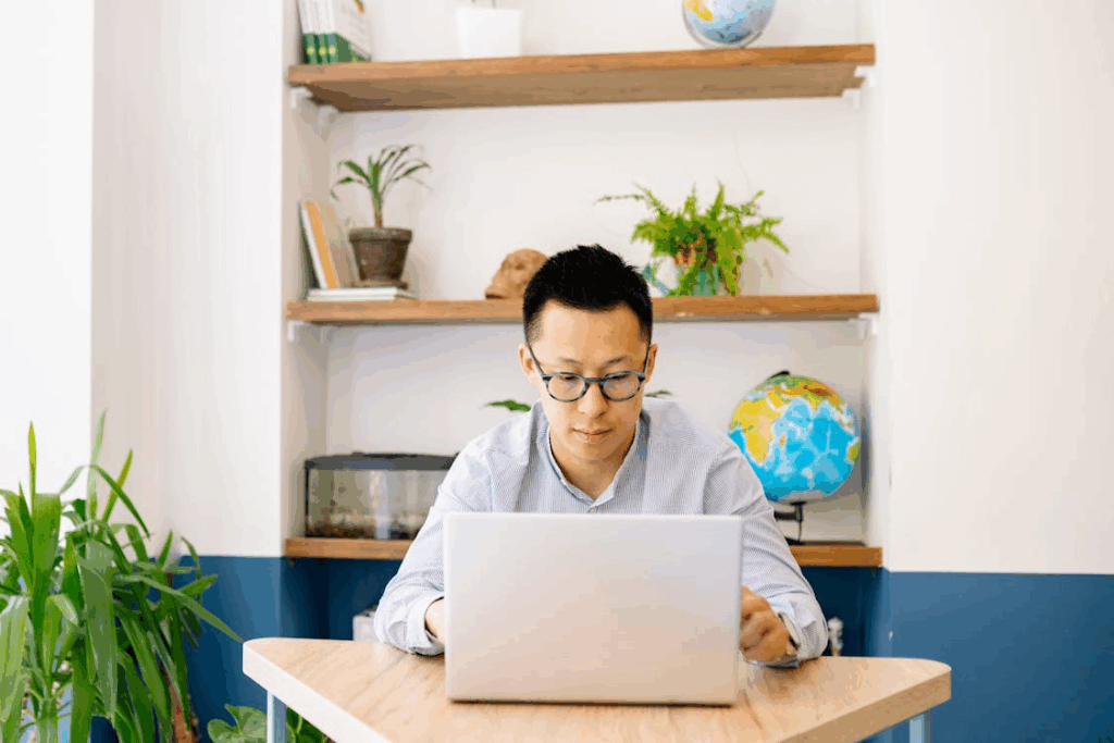 Man working calmly on a laptop at a tidy desk, practicing monotasking in a bright home office.