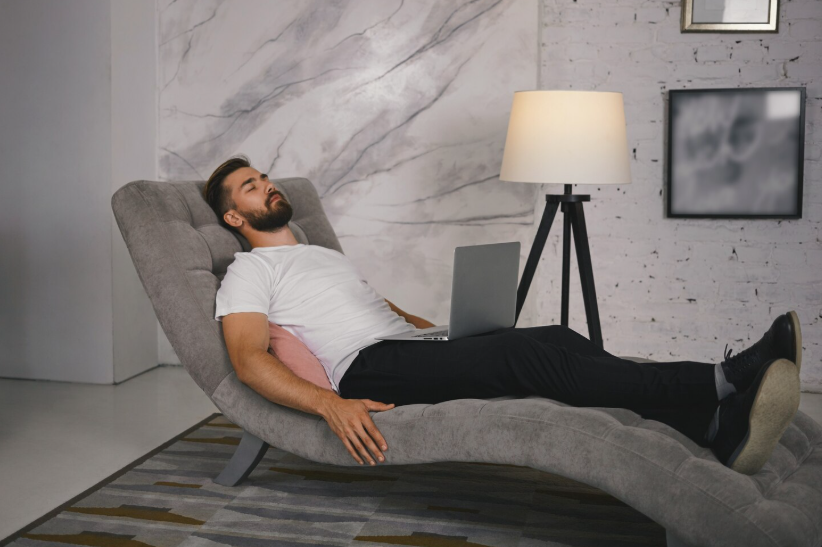 Man reclining on lounge chair taking an intentional rest break from laptop work at home.