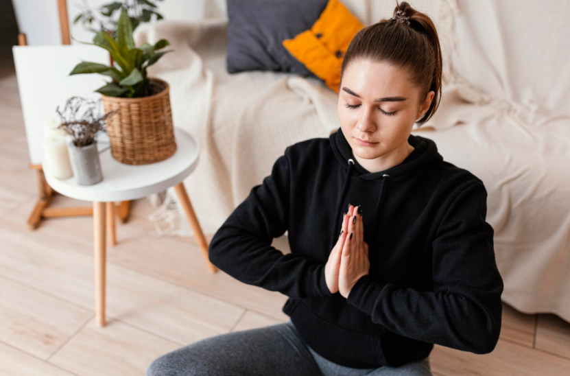 Woman sitting cross-legged on the floor with hands in a prayer pose to find her inner sanctuary.